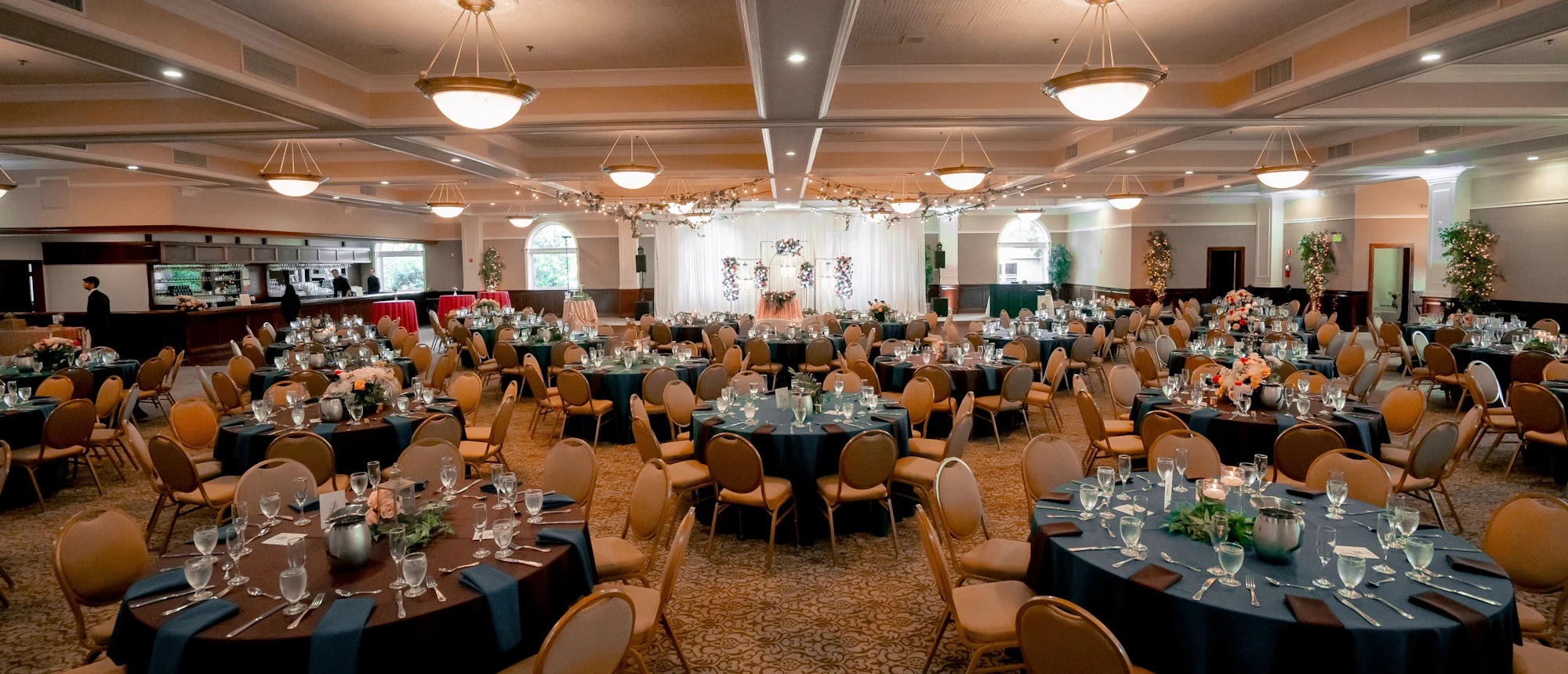 A ballroom set with round tables for a formal dinner